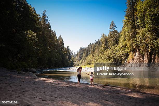 mutter und tochter spielen in der nähe des flusses im wald - oregon landscape stock-fotos und bilder