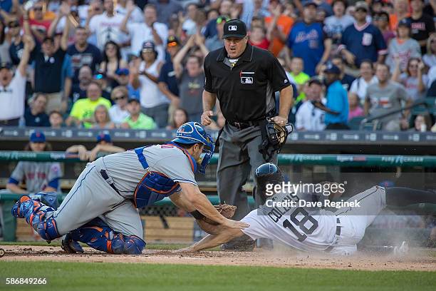 Tyler Collins of the Detroit Tigers beats the tag by catcher Travis d'Arnaud of the New York Mets and score a run in the first inning during a MLB...
