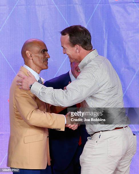 Tony Dungy, former NFL player and head coach, shakes hands with former NFL quarterback Peyton Manning during the NFL Hall of Fame Enshrinement...