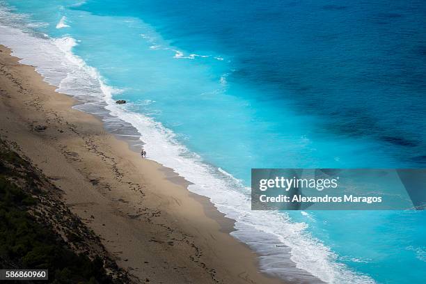 couple walking alone on the beach - alexandros maragos stock pictures, royalty-free photos & images