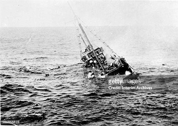 View of the aftermath of the sinking of a Japanese merchant ship by the US Navy submarine USS Tambor, with survivors visible on the ship's rigging,...