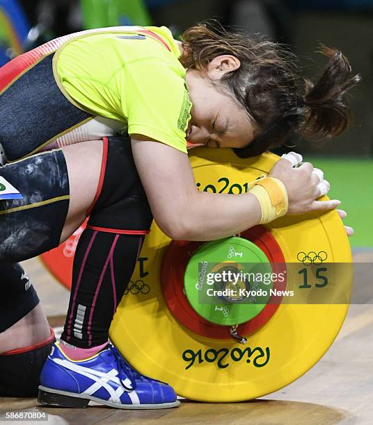 Japanese weightlifter Hiromi Miyake strokes her barbell after a successful jerk of 107 kilograms in the women's 48-kilogram event at the Rio de...