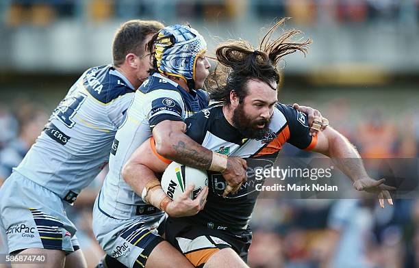 Aaron Woods of the Tigers is tackled during the round 22 NRL match between the Wests Tigers and the North Queensland Cowboys at Leichhardt Oval on...