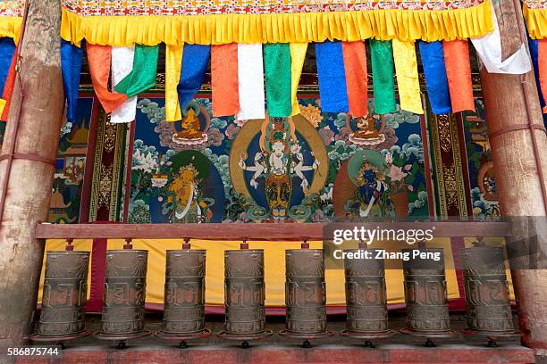 Prayer wheels and mural painting of Tibetan Buddhist figure. Kumbum Monastery is one of the two most important Tibetan Buddhist monasteries outside...