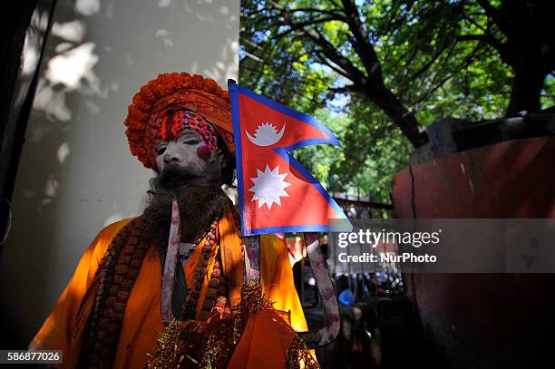 Holy Sashu holds Nepalese National flag at the premies of Nag Pokhari during Nag Panchami or Snake Day Festival celebrated at Naxal, Kathmandu, Nepal...