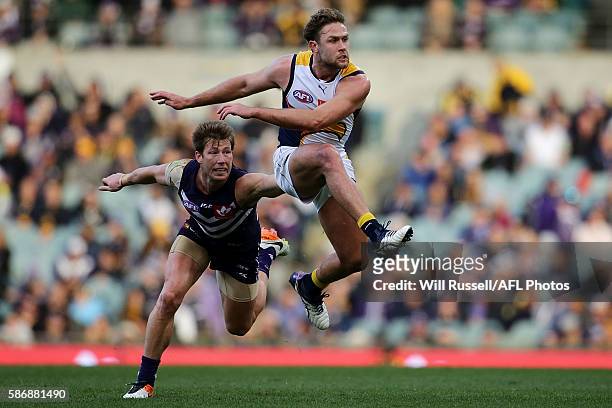 Mark Hutchings of the Eagles kicks the ball under pressure from Lee Spurr of the Dockers during the round 20 AFL match between the Fremantle Dockers...