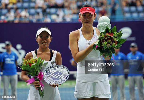 Duan Yingying of China and Vania King of the US pose with their trophies after their singles final match at the Jiangxi Open WTA tennis tournament in...
