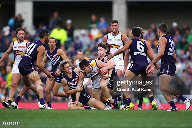 Luke Shuey of the Eagles attempts to break from a tackle by Chris Mayne and Lachie Neale of the Dockers during the round 20 AFL match between the...