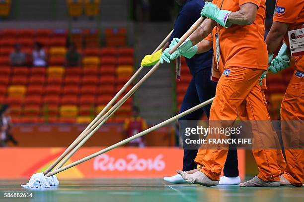 Olympic park employees clean the handball court with the Rio 2016 logo in background ahead of the men's preliminaries Group A handball match Croatia...