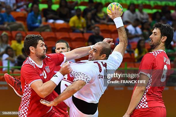 Qatar's pivot Bassel Alrayes vies with Croatia's pivot Jakov Gojun and Croatia's right back Marko Kopljar during the men's preliminaries Group A...