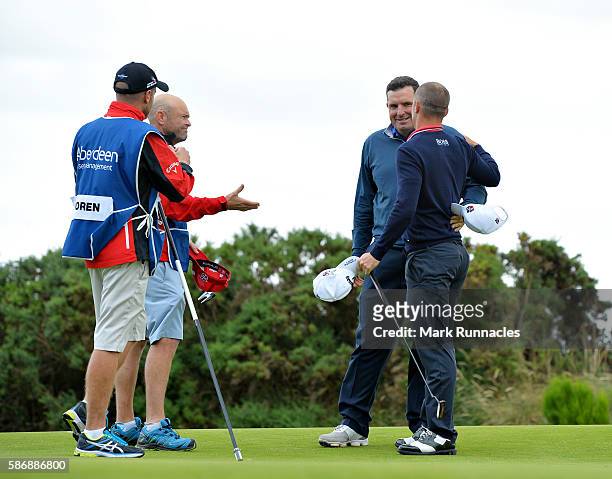 Anthony Wall of England is congratulated by Alex Noren of Sweden and their caddies after he won their match on hole 18 on day four of the Aberdeen...