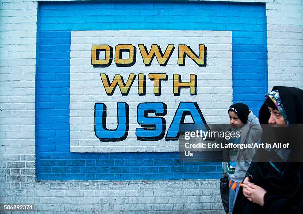 People passing in front of anti-american mural propoganda on the wall of the former united states embassy, central district, tehran, Iran on December...