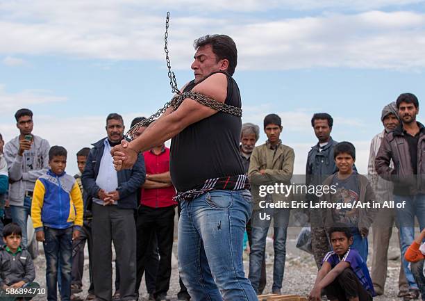 Astrongman struggles to break free of chains at the panjshambe bazar thursday market, hormozgan, minab, Iran on December 31, 2015 in Minab, Iran.