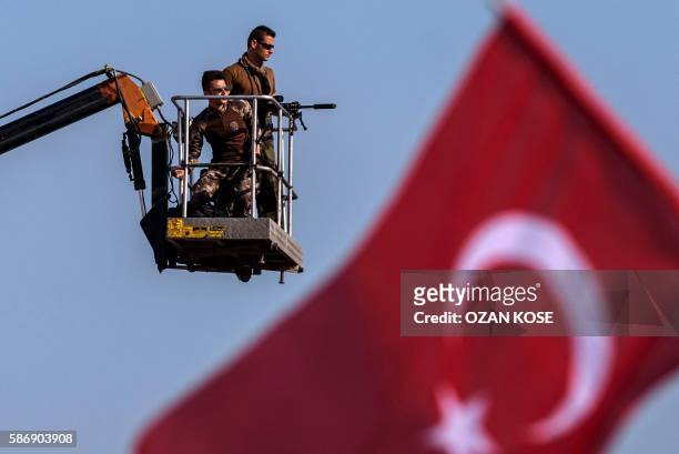 Turkish special force police officers stand guard as people wawe Turkish national flags on August 7, 2016 in Istanbul during a rally against failed...