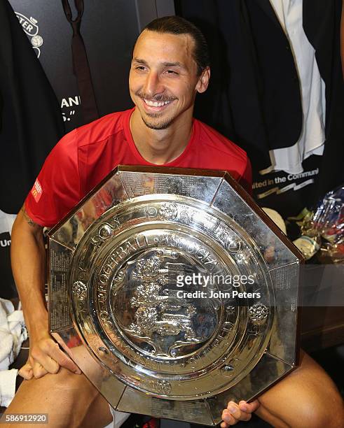 Zlatan Ibrahimovic of Manchester United poses with the Community Shield trophy in the dressing room after the FA Community Shield match between...