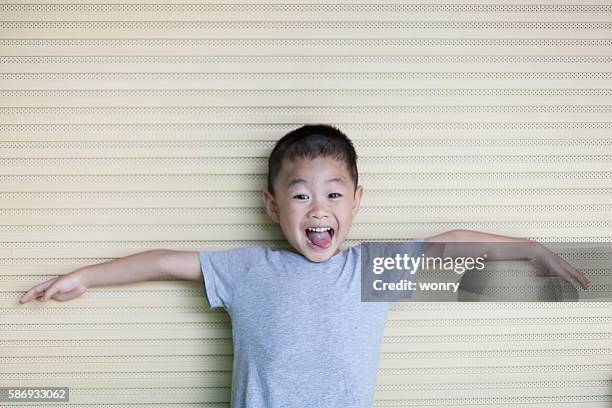 asian boy spread arms white leaning wall - gray shirt stock pictures, royalty-free photos & images