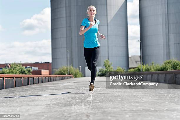 young woman running in an urban environment. - striding stock pictures, royalty-free photos & images