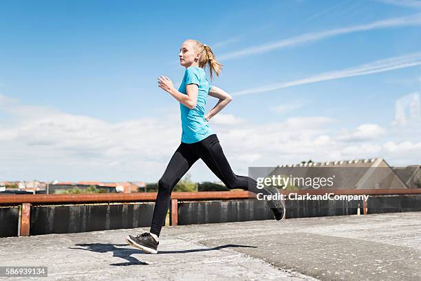 young woman running in an urban environment. - striding stock pictures, royalty-free photos & images
