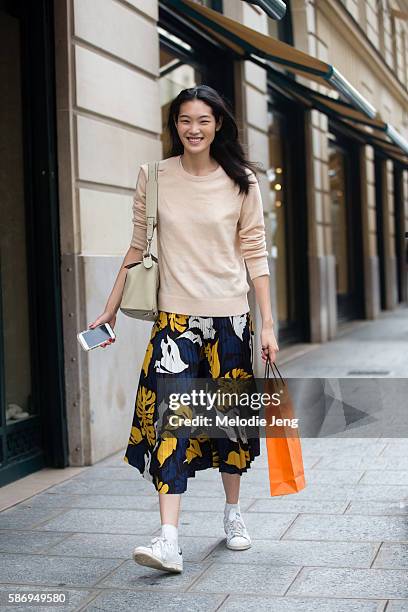 Japanese model Chiharu Okunugi wears a cream-colored sweater, a floral pleated skirt, and Adidas Stan Smith sneakers after the Hermes Resort SS17...