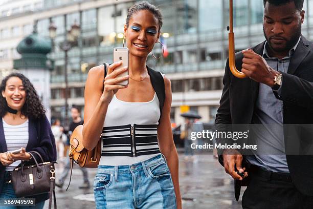 Puerto Rican supermodel Joan Smalls takes an iPhone Snapchat photo and wears light-blue eye makeup by Pat McGrath, hoop earrings, a H&M white tank...