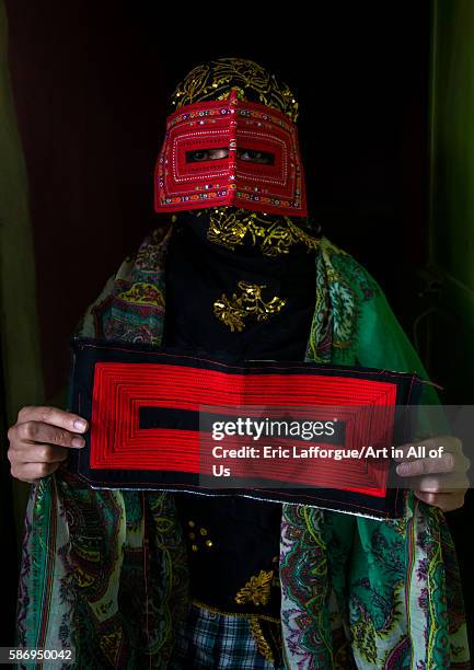 Abandari woman wearing a traditional mask called the burqa and showing one she is sewing, hormozgan, minab, Iran on December 31, 2015 in Minab, Iran.