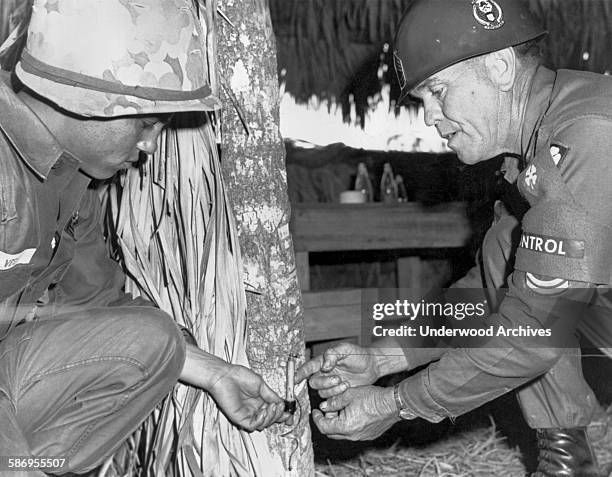 An Army instructor shows a recruit how to deactivate a trip wire used by the Viet Cong in Vietnam, 1967.