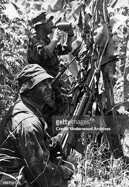 Two Navy SEALs pause for a drink of water during Operation Crimson Tide in the Vinh Binh Province southwest of Saigon, Vinh Binh, Viet Nam, December...
