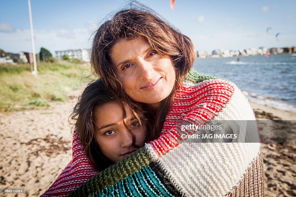 Mother and daughter wrapped in a blanket at beach