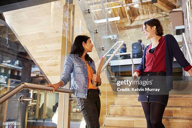 two colleagues chat on stairs in modern office - incidental people asian stock pictures, royalty-free photos & images