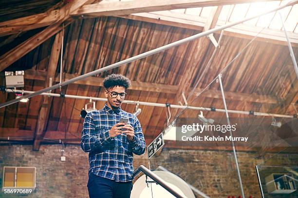 a young mixed race creative professional on phone - mobile phone reading low angle stock-fotos und bilder