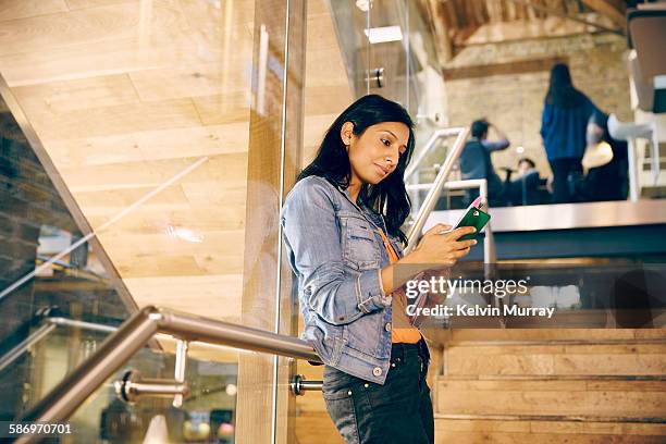 a young, female, asian professional checks phone - enviar actividad fotografías e imágenes de stock