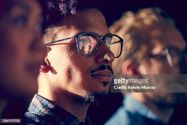 a mixed race male employee watches presentation - gelegenheit stock-fotos und bilder