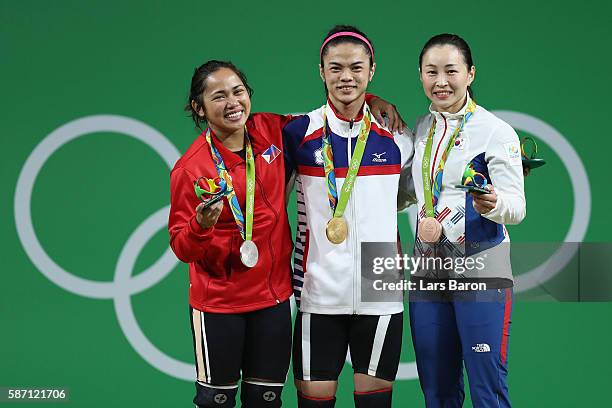Gold medalist, Shu-Ching Hsu of Chinese Taipei, silver medalist Hidilyn Diaz of the Philippines and bronze medalist Jin Hee Yoon of Korea celebrate...
