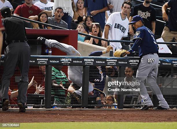 Jonathan Villar of the Milwaukee Brewers makes a diving catch over the railing in front of teammate Orlando Arcia on a pop foul by Tuffy Gosewisch of...
