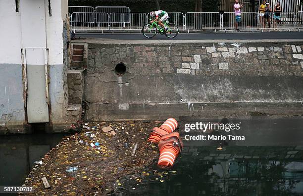 Cyclist rides past an 'eco barrier' along a polluted canal in the Leblon neighborhood during the Women's Road Race on Day 2 of the Rio 2016 Olympic...