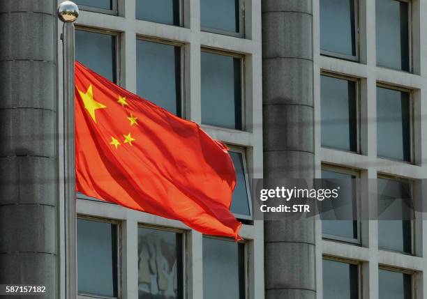 The Chinese national flag is seen on a flagpole in Beijing on August 8, 2016. - Most of the five stars on the Chinese flags being used at medal...