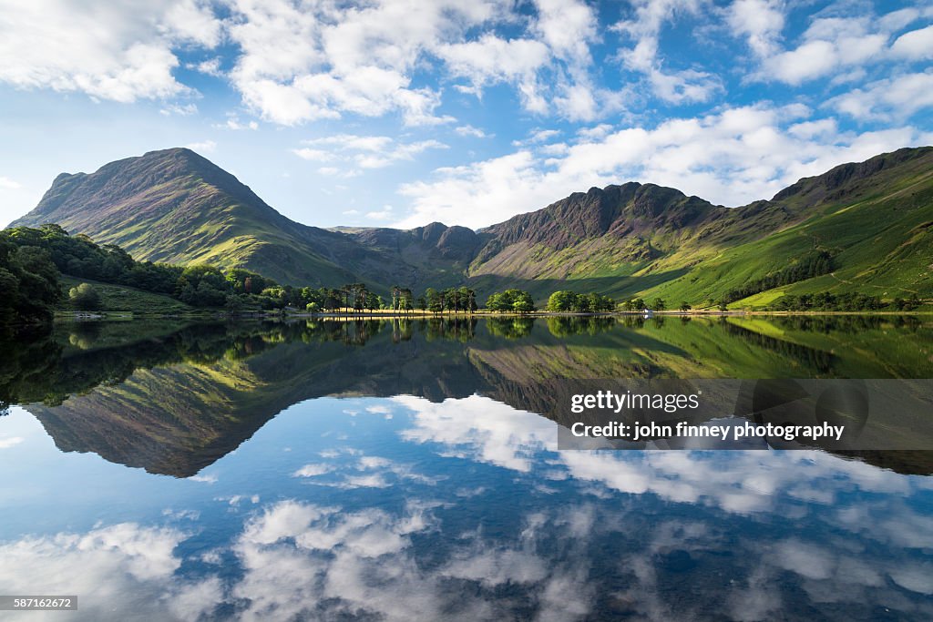 Buttermere lake early morning reflections. A beautiful summer morning with Fleetwith Pike and Haystacks mountains covered in purple heather. Lake District National park. UK. Europe.