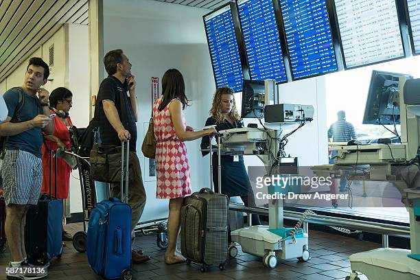 Delta employee helps travelers at a mobile check-in station that was set up near the Delta check-in counter at LaGuardia Airport , August 8, 2016 in...