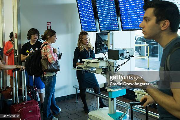 Delta employee helps travelers at a mobile check-in station that was set up near the Delta check-in counter at LaGuardia Airport , August 8, 2016 in...