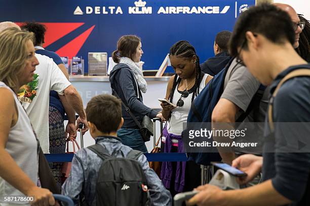 Travelers wait in line at the Delta check-in counter at LaGuardia Airport , August 8, 2016 in the Queens borough of New York City. Delta flights...