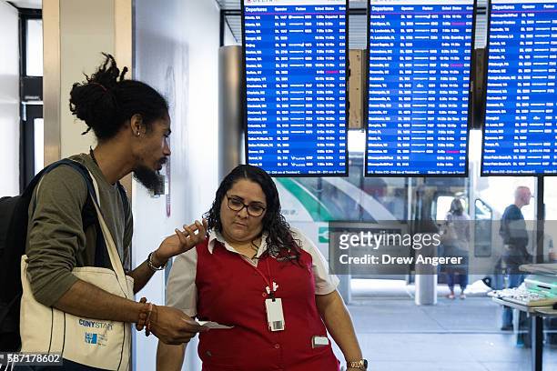 Delta employee helps a traveler near the Delta check-in counter at LaGuardia Airport , August 8, 2016 in the Queens borough of New York City. Delta...