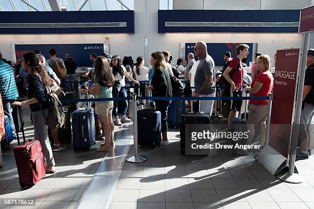 Travelers wait in line at the Delta baggage drop at LaGuardia Airport , August 8, 2016 in the Queens borough of New York City. Delta flights around...