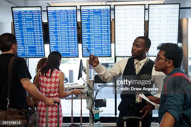 Delta employee helps travelers near the Delta check-in counter at LaGuardia Airport , August 8, 2016 in the Queens borough of New York City. Delta...