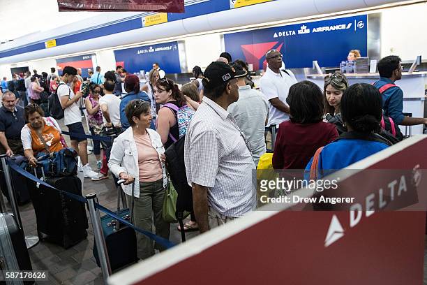 Travelers wait in line at the Delta check-in counter at LaGuardia Airport , August 8, 2016 in the Queens borough of New York City. Delta flights...