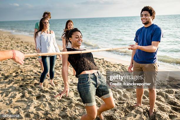 eine gruppe von menschen spielen am strand schwebe - limbo stock-fotos und bilder