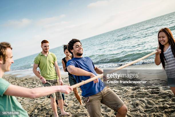 grupo de gente jugando al limbo en la playa - limbo fotografías e imágenes de stock
