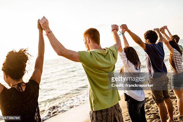 volunteer with arm raised at sunset - religion stock pictures, royalty-free photos & images