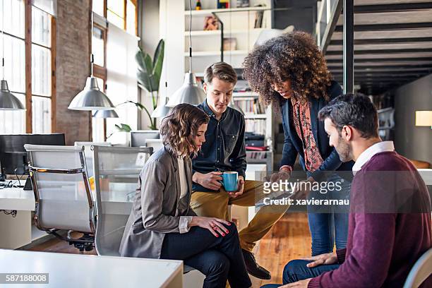 young creative coworkers discussing project on digital tablet - insight guidance stock pictures, royalty-free photos & images
