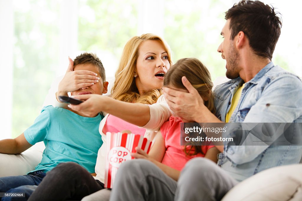 Parents cover their children's eyes while watching TV