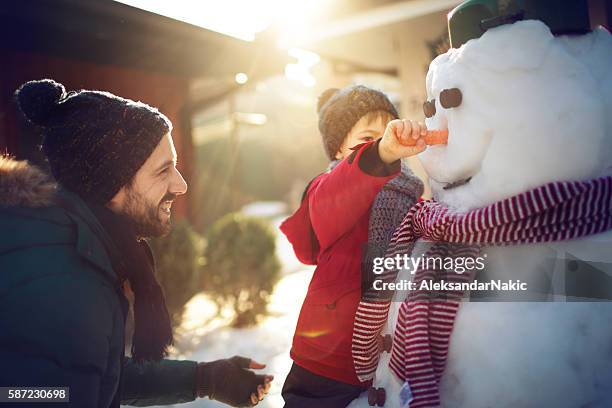 mit meinem vater einen schneemann machen - snowman stock-fotos und bilder